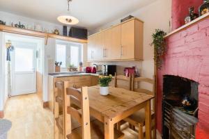 a kitchen with a wooden table and a red brick wall at Fergies Canal Side Cottage in Warwick
