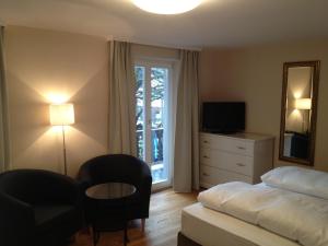 sypialnia z łóżkiem, krzesłem i oknem w obiekcie Alpenhof Landhotel Restaurant w mieście Oberaudorf