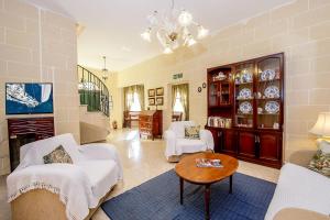 a living room with white chairs and a table at Ta Joseph in Xewkija