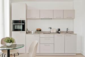 una cucina con mobili bianchi e tavolo di The Chronicle by Supercity Aparthotels a Londra