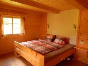 ein Schlafzimmer mit einem Bett in einem Blockhaus in der Unterkunft Kristlisalm in Hopfgarten in Defereggen