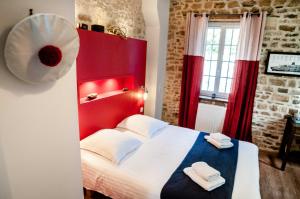 - une chambre avec une tête de lit rouge et 2 serviettes sur un lit dans l'établissement La demeure d'Ervée, à Isigny-sur-Mer