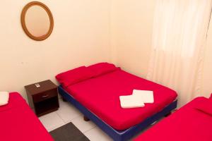 ein kleines Zimmer mit einem roten Bett und einem Spiegel in der Unterkunft El Paraiso in Montañita