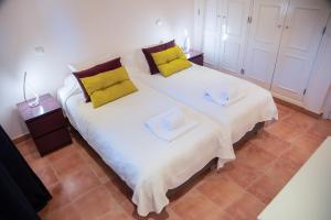 a bedroom with a large white bed with yellow pillows at Colina Verde Resort in Moncarapacho