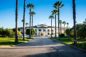 a large white house with palm trees on a street at Colina Verde Resort in Moncarapacho