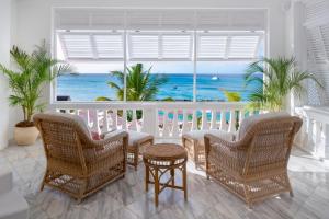 a room with a balcony with a view of the ocean at Cobblers Cove - Barbados in Saint Peter
