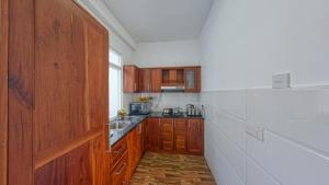 una pequeña cocina con armarios de madera y fregadero en Ocean Breeze Apartment Colombo, en Colombo