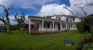 a white house with a green yard at Quinta das Bolas in Ponta Delgada