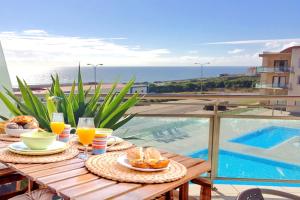 una mesa con comida y bebida en la parte superior de un balcón en Sun Dreams Ericeira Apartment, en Ericeira