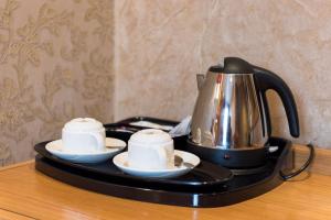 un bollitore per il tè e due tazze su un vassoio su un tavolo di The Montana Hotel a Londra