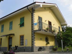 a yellow house with a balcony and a dog at B&B Pervinca in Rocca Grimalda