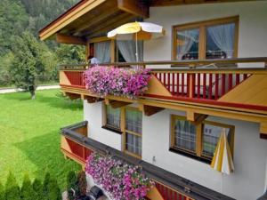 un edificio con fiori sui balconi e un ombrellone di Apartment Sonnenau a Zell am Ziller