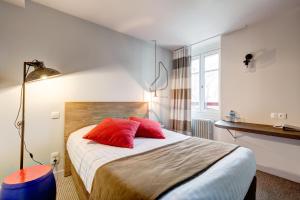a bedroom with a bed with two red pillows at Hôtel Ar Iniz in Saint Malo