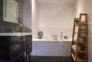 een badkamer met een wastafel en een bad bij Haarlem Hotel Suites in Haarlem