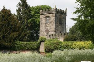 una antigua torre de ladrillo en un jardín con arbustos en Honeysuckle in Crayke YO61 4TE, en York