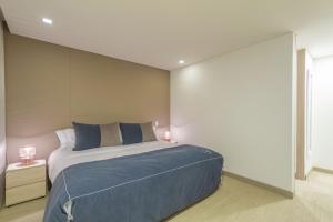 a bedroom with a large bed with blue pillows at Apartametos FACILE in Bogotá