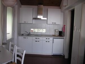 a white kitchen with white cabinets and a table at Apartma Ravbar Portorož in Portorož