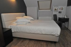 a bed with white sheets and pillows in a bedroom at Hotel Palace in Poperinge