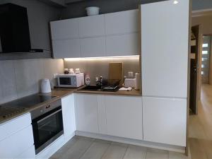 uma cozinha com armários brancos e um micro-ondas em Apartamenty Willa Nawigator em Gdynia