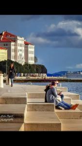 two people sitting on the steps near the water at Apartment Heart of City Lola in Zadar