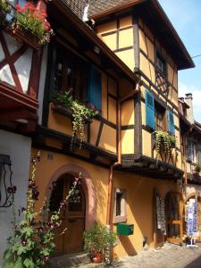 un vieux bâtiment avec des fleurs dans les boîtes aux fenêtres dans l'établissement Gîte de charme sur les remparts, à Eguisheim