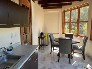a kitchen with a sink and a table with chairs at CORTIJO LA CASONA & Bungalow al Pie de la Montaña in San Cristóbal de Las Casas