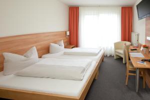 ein Hotelzimmer mit 2 Betten und einem Schreibtisch in der Unterkunft Hotel Weissach Am Neuenbühl in Weissach
