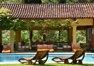 2 sillas junto a una piscina con cenador en Maison de Campagne, Chambres D'Hôtes - Itaipava, en Itaipava