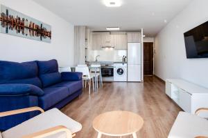 a living room with a blue couch and a kitchen at Vistas al Mar in Alicante