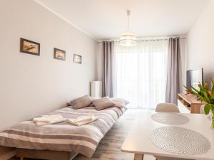 biały pokój z łóżkiem i stołem w obiekcie Apartament Rybacka 12A/68, Kołobrzeg w Kołobrzegu