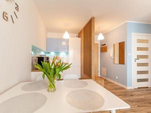 jadalnia z białym stołem i wazą kwiatów w obiekcie Apartament Rybacka 12A/68, Kołobrzeg w Kołobrzegu