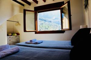 a bedroom with two beds and a large window at Can Pera Accommodation - TI in Fornalutx