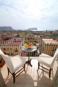 einen Balkon mit 2 Stühlen und einem Tisch mit Obst darauf in der Unterkunft Sibilla appartamento in Neapel