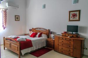 um quarto com uma cama e uma cómoda com uma televisão em Refugio no Campo - AL 1683 em Rapoula do Côa