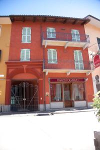 a red building with a balcony on a street at Hotel Palazzo Di Mezzo in Carrù