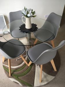 two chairs and a glass table with a vase of flowers at Blue Sky Apartments@The Centrium, Woking in Woking