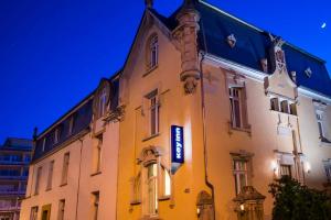 a large yellow building with a blue sign on it at Key Inn serviced residences Belair in Luxembourg