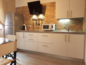 uma cozinha com armários brancos e um frigorífico de aço inoxidável em Moro Dal Castel - Appartamento Al Moro em Castelnuovo del Garda