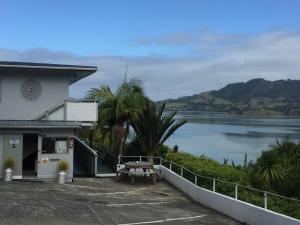 a building with a picnic table in front of a lake at Pacific Harbour Lodge in Whangaroa
