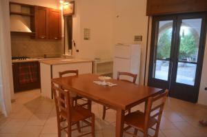 een keuken met een houten tafel en stoelen en een koelkast bij Villetta Sakapo' in Corigliano dʼOtranto
