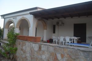 d'une terrasse avec des chaises et des tables blanches sur un mur. dans l'établissement Villetta Sakapo', à Corigliano dʼOtranto