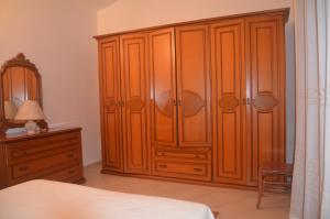 una camera da letto con un grande armadio in legno e un comò di Villetta Sakapo' a Corigliano dʼOtranto