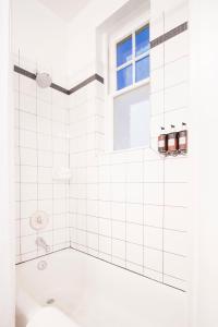 a white tiled bathroom with a tub and a window at The Armstrong Hotel in Fort Collins