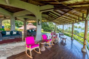 a covered porch with pink chairs and a table at La Cusinga Lodge in Uvita