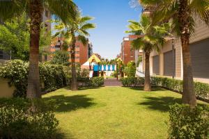 une cour avec des palmiers et une aire de jeux dans l'établissement EnjoyGranada LUJO Piscina y Parking, à Grenade