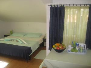 杜布羅夫尼克的住宿－尼科利娜客房酒店，一间卧室配有一张床和一张桌子及一碗水果