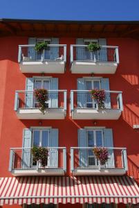 czerwony budynek z skrzyniami kwiatowymi na balkonach w obiekcie Hotel Sport w mieście Coredo