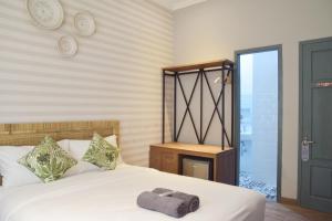 a bedroom with a white bed with a towel on it at Grhatama Guest House in Yogyakarta