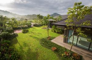 una imagen de un jardín junto a una casa en At Green Gallery, en Si Racha