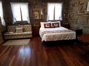 a bedroom with a bed and a couch and windows at 1860 Wine Country Cottages in Springton